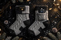 Chaussettes chauffantes rechargeables pour homme grises et noires présentées sur fond noir et doré DULUXE, batterie visible, ambiance hivernale premium