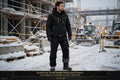 Homme portant le pantalon de travail noir doublé polaire sur un chantier hivernal, présentation premium noir et doré DULUXE