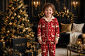 Pyjama polaire de Noël pour enfant porté près du sapin décoré, motifs rennes et flocons, ambiance des Fêtes chaleureuse DULUXE noir et doré