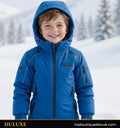 Enfant souriant en combinaison de ski intégrale bleue DULUXE dans la neige, visuel principal