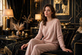 Femme en ensemble détente beige rosé en maille douce façon cachemire, assise sur un canapé dans un salon noir et doré DULUXE