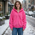Hoodie à capuche-cagoule DULUXE rose vif en polaire, capuche ouverte, porté dans une rue enneigée, visuel principal