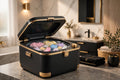 Mini lave-linge pliable portable noir et doré rempli de petites pièces colorées dans une salle de bain lumineuse