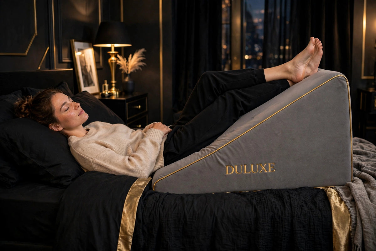 Jambes surélevées et détendues sur le Coussin de Position DULUXE gris, position de repos au lit