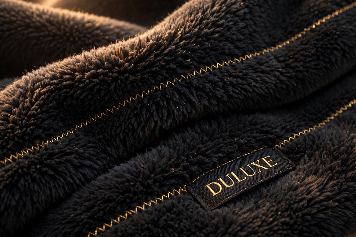 Gros plan sur le tissu doux et enveloppant de l'écharpe chauffante, texture moelleuse noire aux finitions dorées