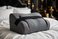 Oreiller pour Genoux en Mousse à Mémoire DULUXE – forme en coin grise avec sangle, sur un lit premium