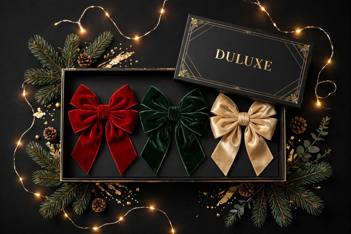 Trois grands nœuds de Noël rouge, vert et doré présentés dans un coffret cadeau noir et doré DULUXE avec branches de pin