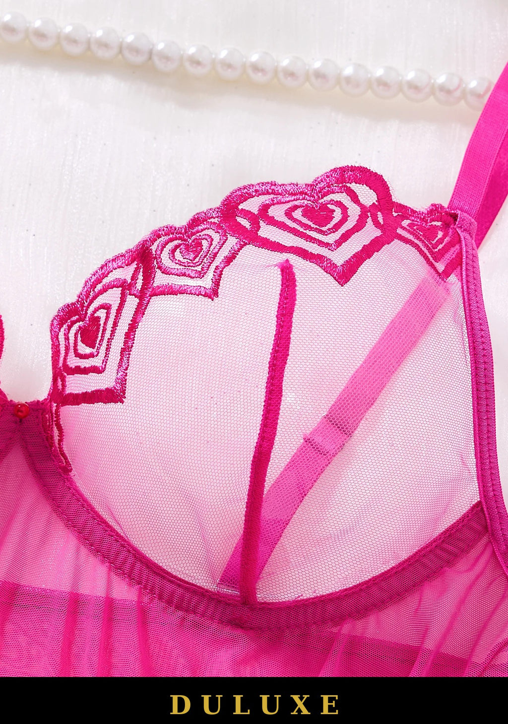 Détail de la dentelle brodée en motifs de cœurs sur le bonnet de la nuisette rose fuchsia DULUXE