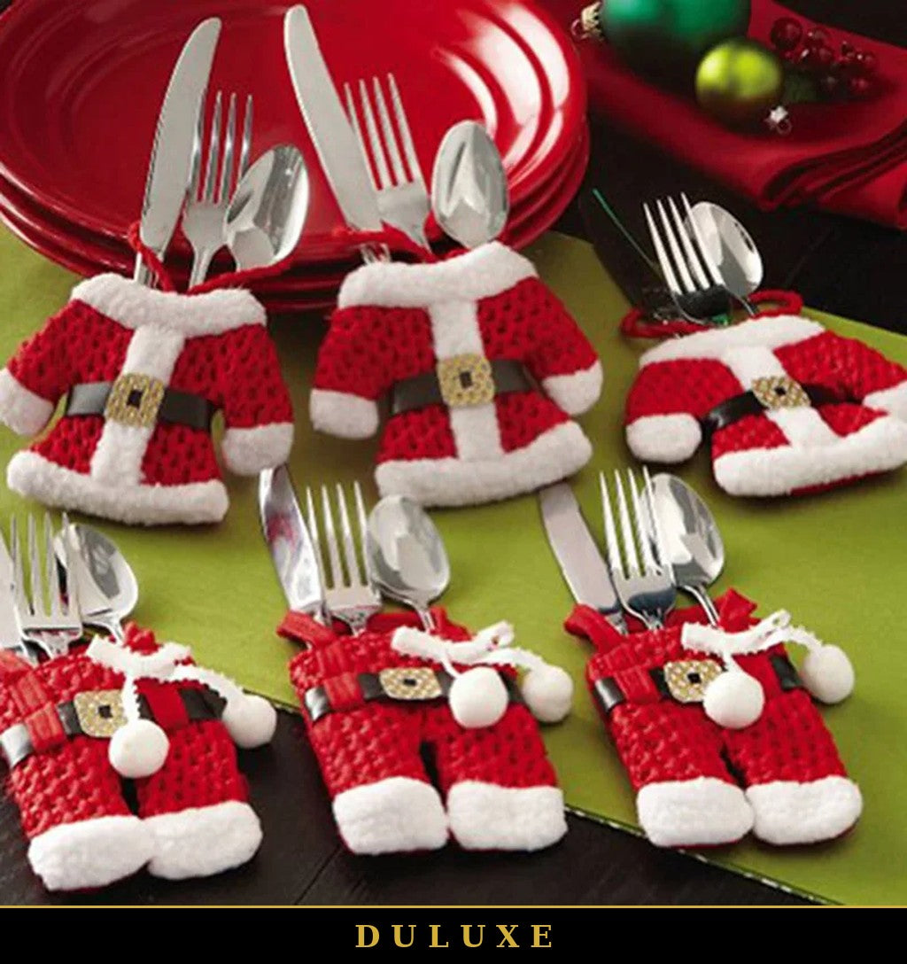 Porte-couverts costume de Père Noël DULUXE sur une table des fêtes avec assiettes rouges