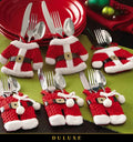 Porte-couverts costume de Père Noël DULUXE sur une table des fêtes avec assiettes rouges