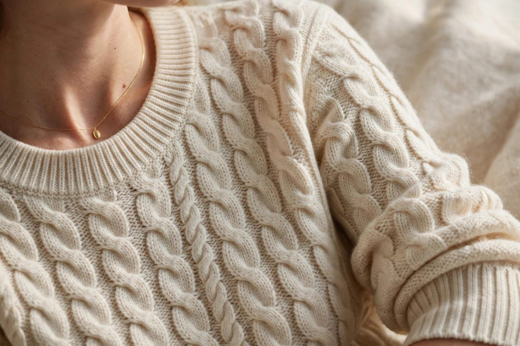 Détail du col rond et de la manche du pull crème en maille torsadée DULUXE pour femme