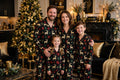 Famille en pyjamas de Noël assortis devant un sapin décoré, photo de famille souriante