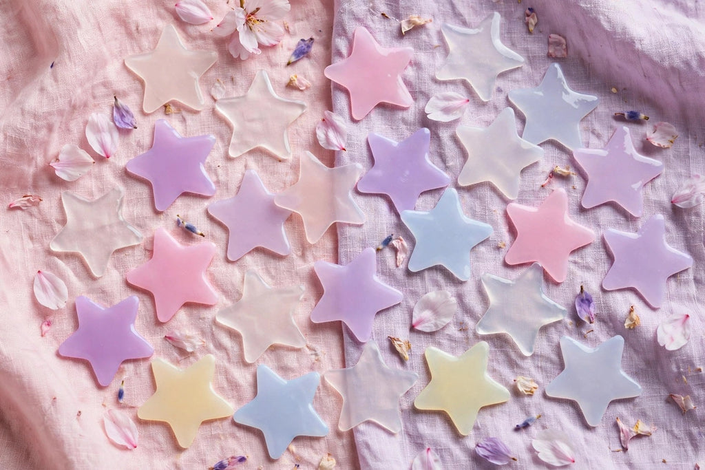 Flat lay pastel de patchs étoiles hydrocolloïdes multicolores avec pétales de fleurs.