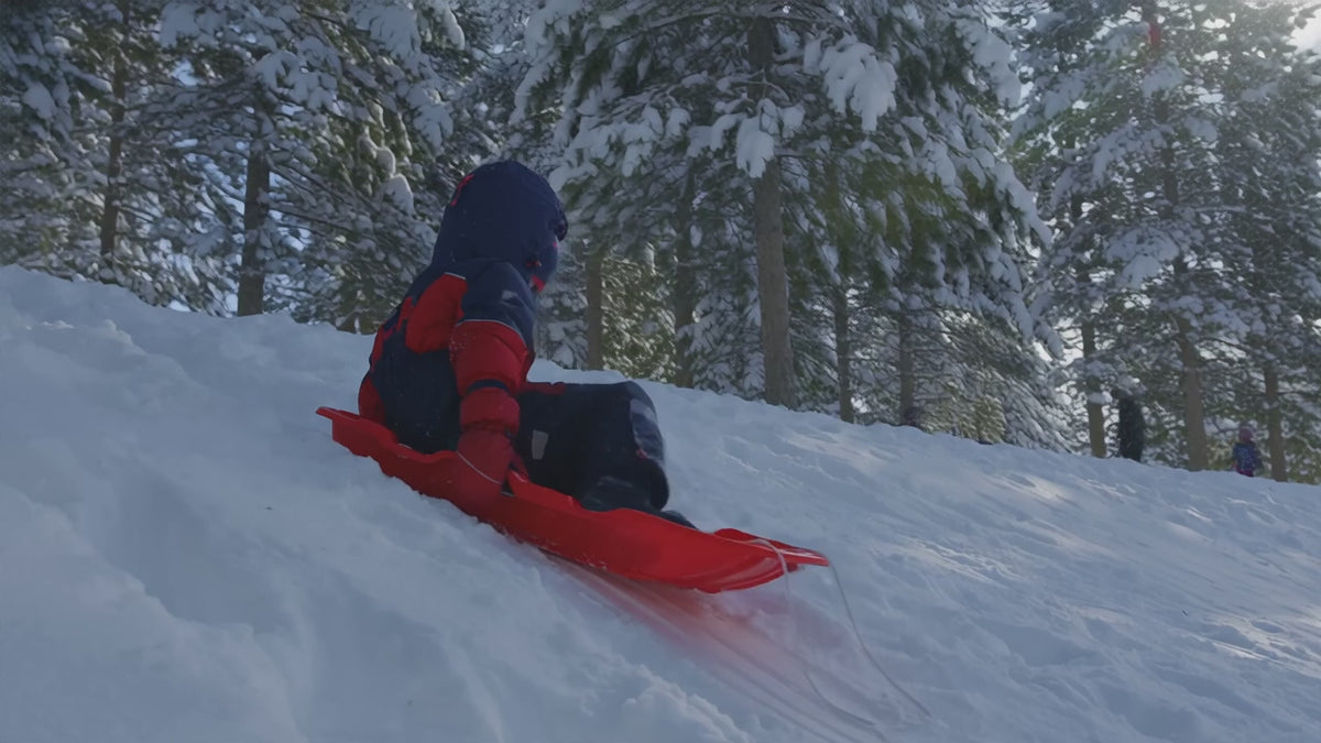 Vidéo démo de la salopette de neige DULUXE : enfant qui glisse en traîneau et se relève en riant